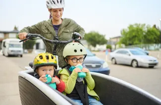 deux enfants dans une remoque accrochée au velo de leur maman