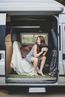 femme dans un fourgon aménagé qui boit une tasse de café