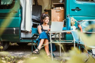 femme sur un ordinateur devant un camping car