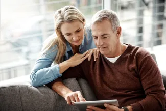 couple assis sur un canapé qui regarde une tablette
