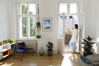 femme qui regarde par une porte fenetre de son appartement