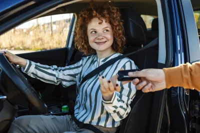 jeune conductrice a qui on tend une clé de voiture