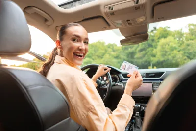 femme au volant d'une voiture avec son permis de conduire